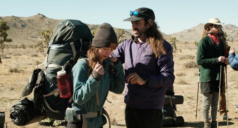 one person helps another adjust their backpacking in Joshua Tree National Park